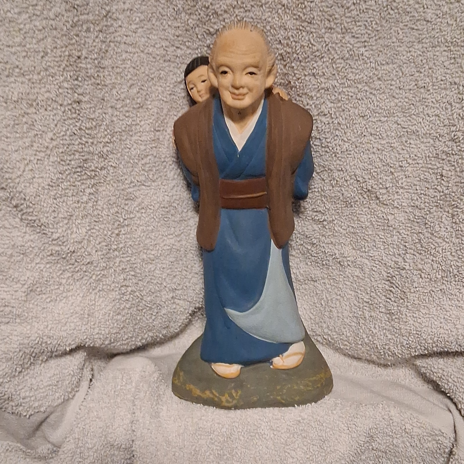 Uncommon Ceramic Hand Painted Figurine Of An Elderly Man Carrying A Small Child