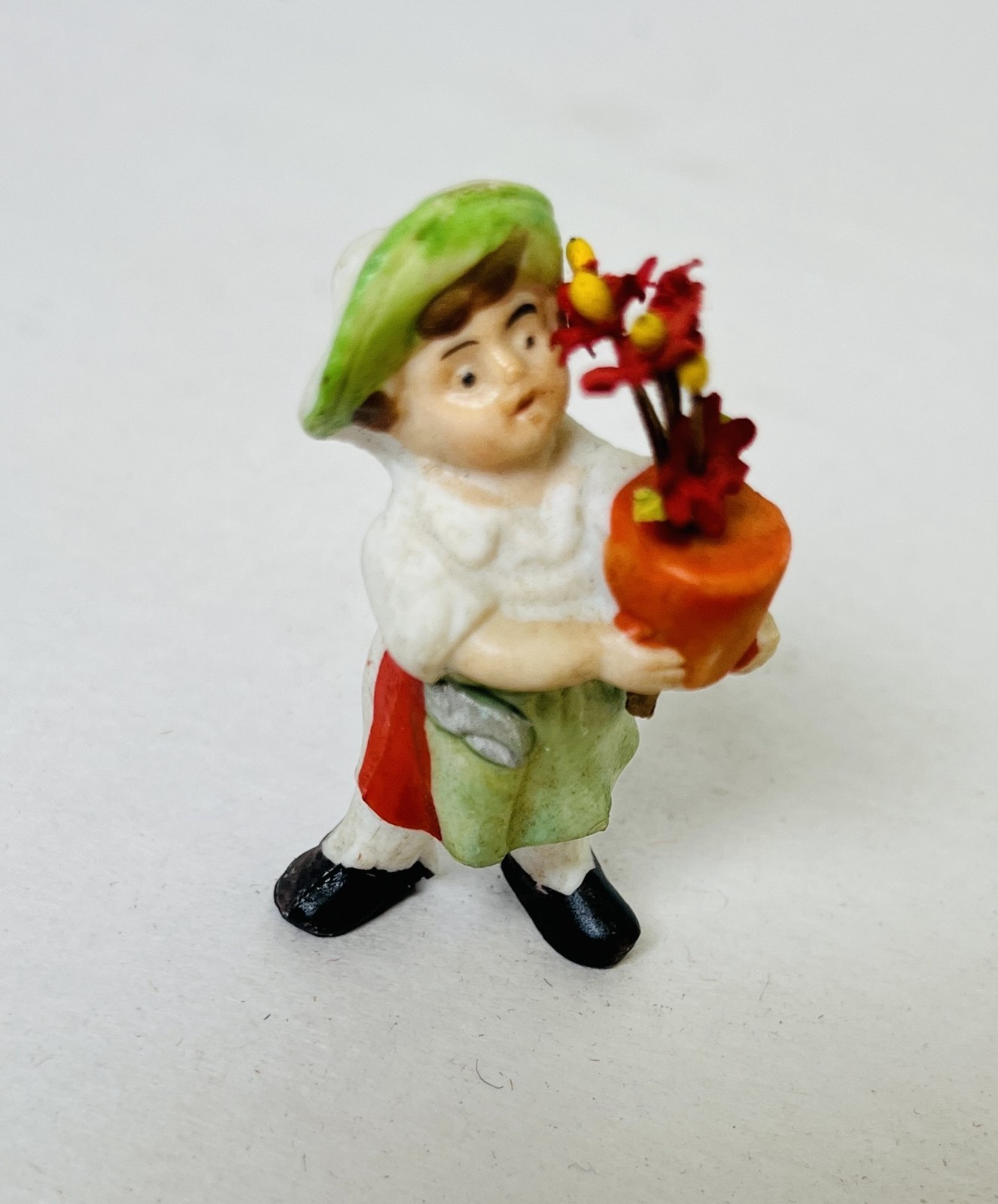 Antique Small porcelain Figure Holding A Pot Of Flowers 2″ Tall