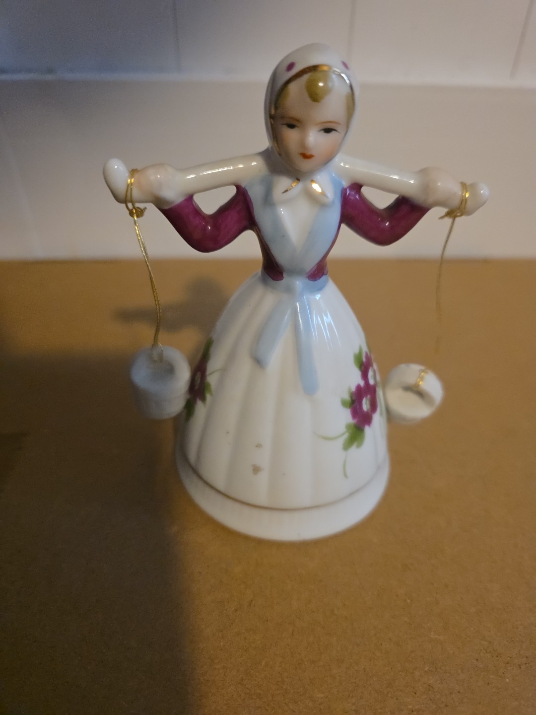 vintage porcelain bell figurine depicting a maiden in a bonnet carrying water