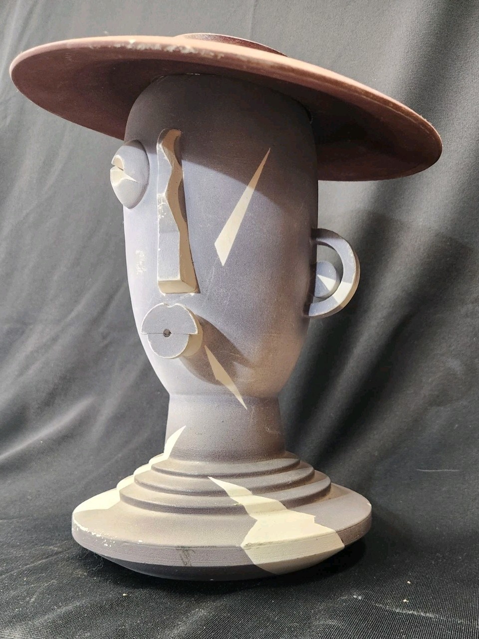 Design: The piece features an abstract, modernist design with simplified facial