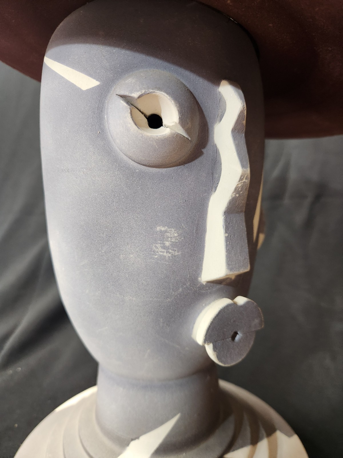 Design: The piece features an abstract, modernist design with simplified facial