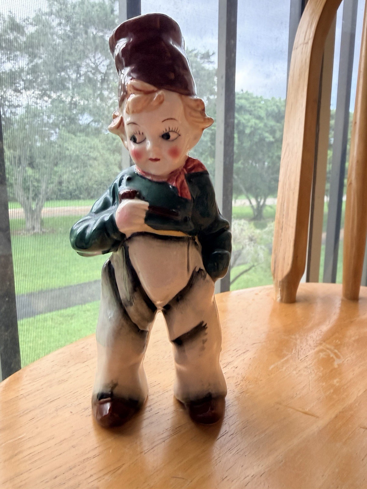 Vintage Ceramic Boy Figurine in a tall hat, green jacket, and white trousers