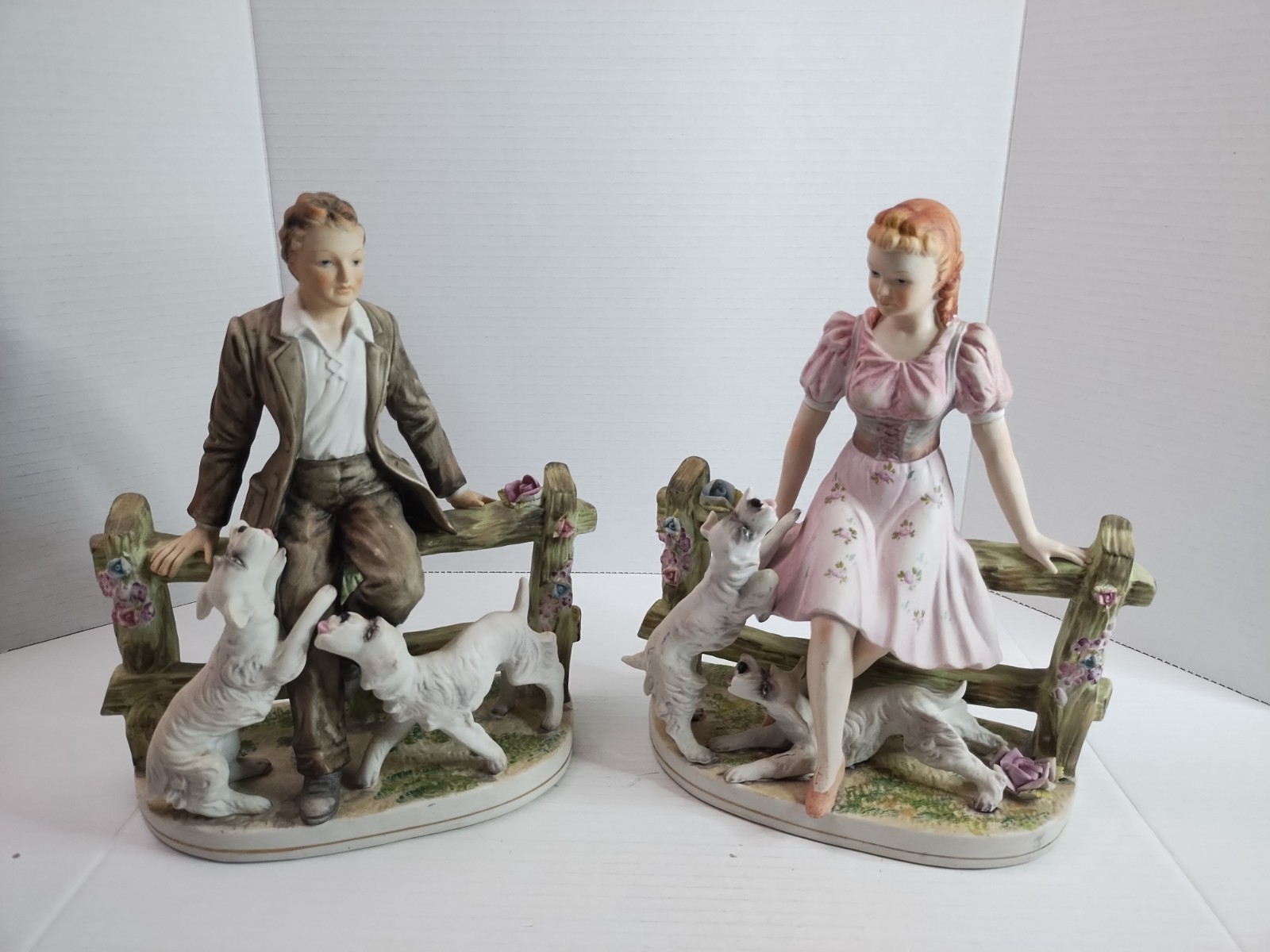 Vintage LRG Pair Of Ucagco 11”x9” Man & Woman on fence with dogs Bisque Figurine