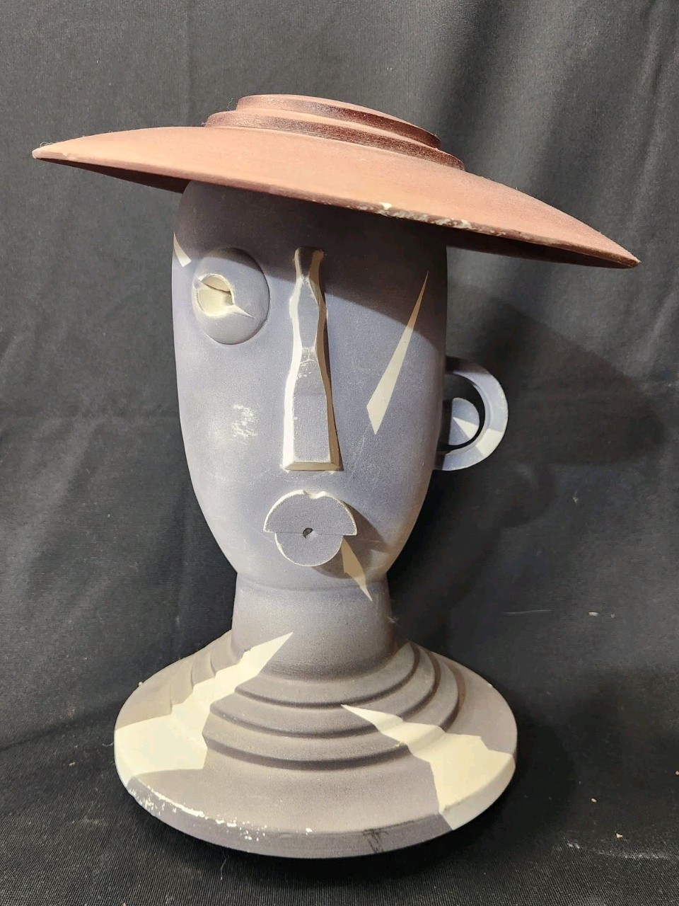 Design: The piece features an abstract, modernist design with simplified facial