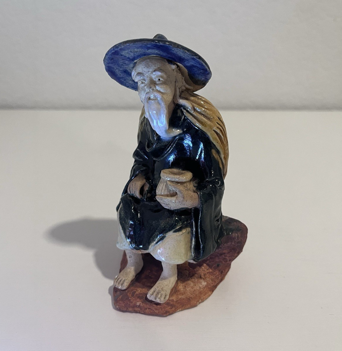 Vintage Chinese Ceramic Seated Mudman Figurine w/ Blue Hat Holding Pot
