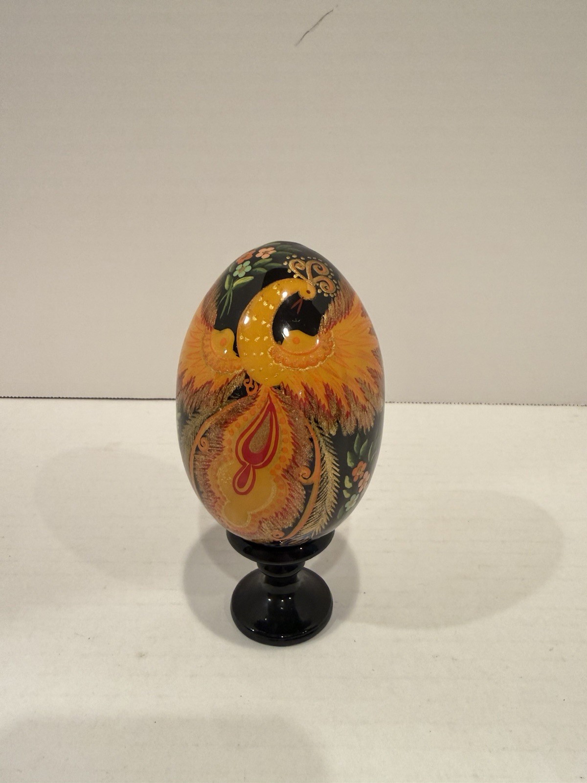 Traditional hand-painted Firebird Slavic Easter egg on a matching pedestal stand