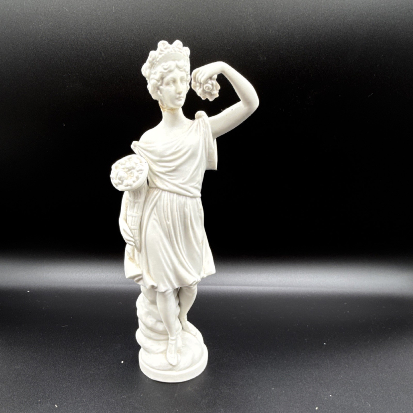 White porcelain figurine of a woman with cornucopia and carved details