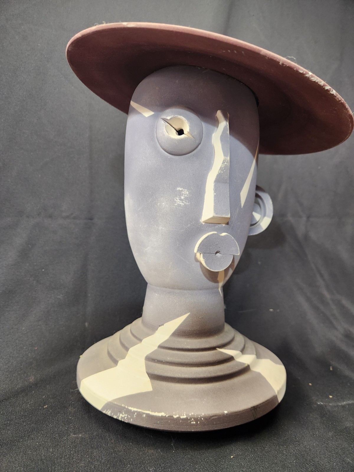 Design: The piece features an abstract, modernist design with simplified facial