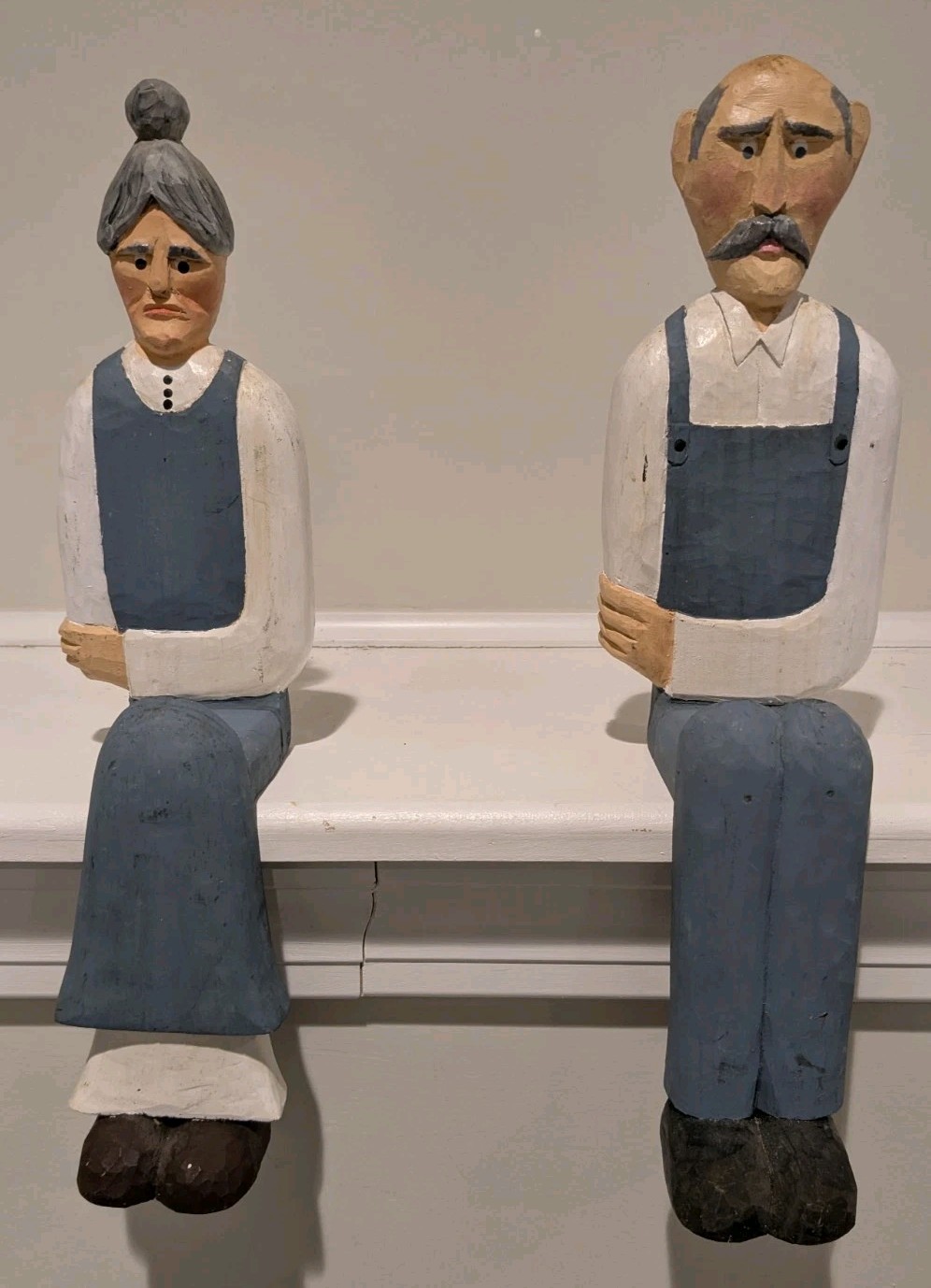 Handmade, hand-painted wood carvings of a seated elderly couple