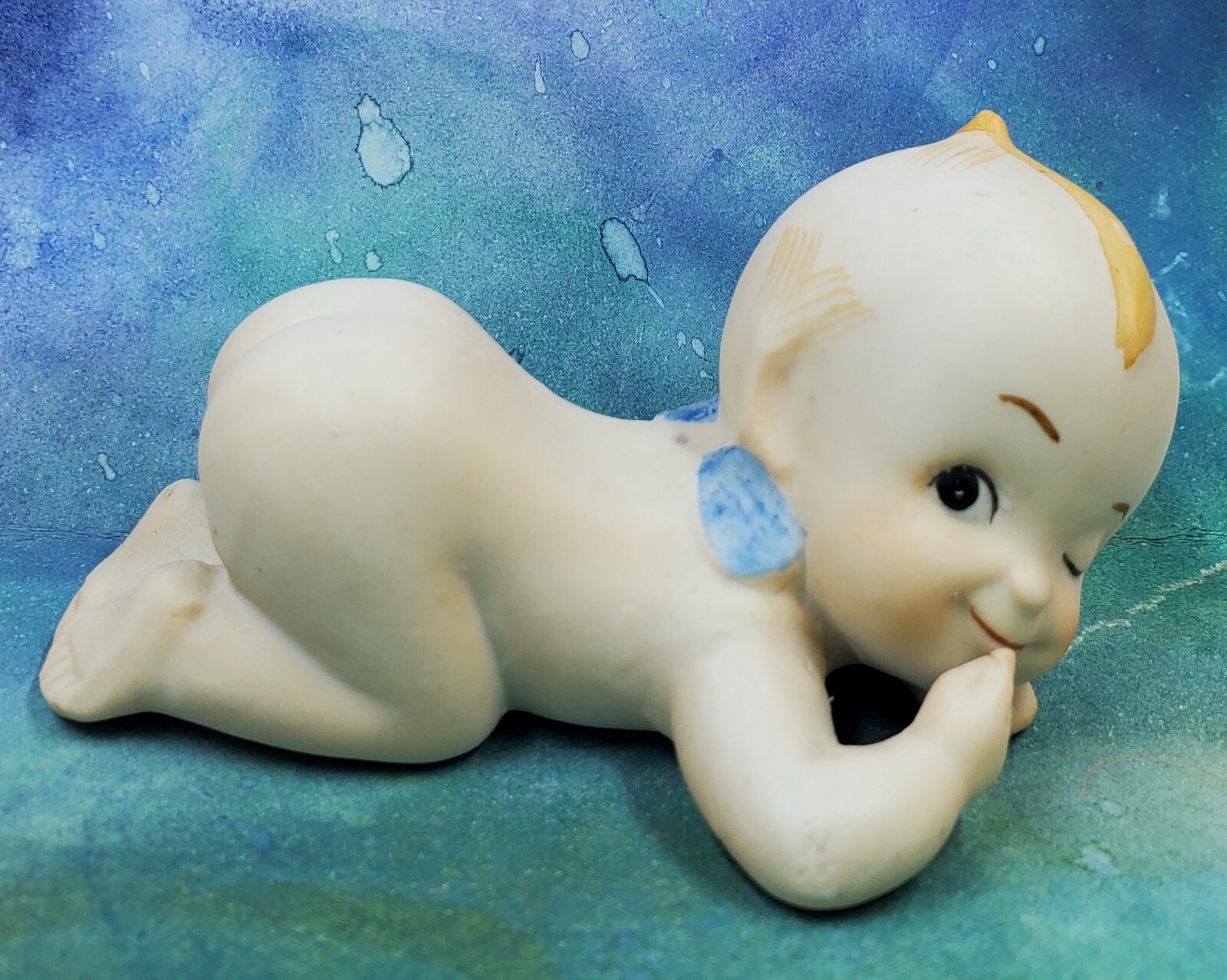 KE1 Porcelain Kewpie Winking Laying On Belly Finger At Mouth Figurine 1.75″ X 3″