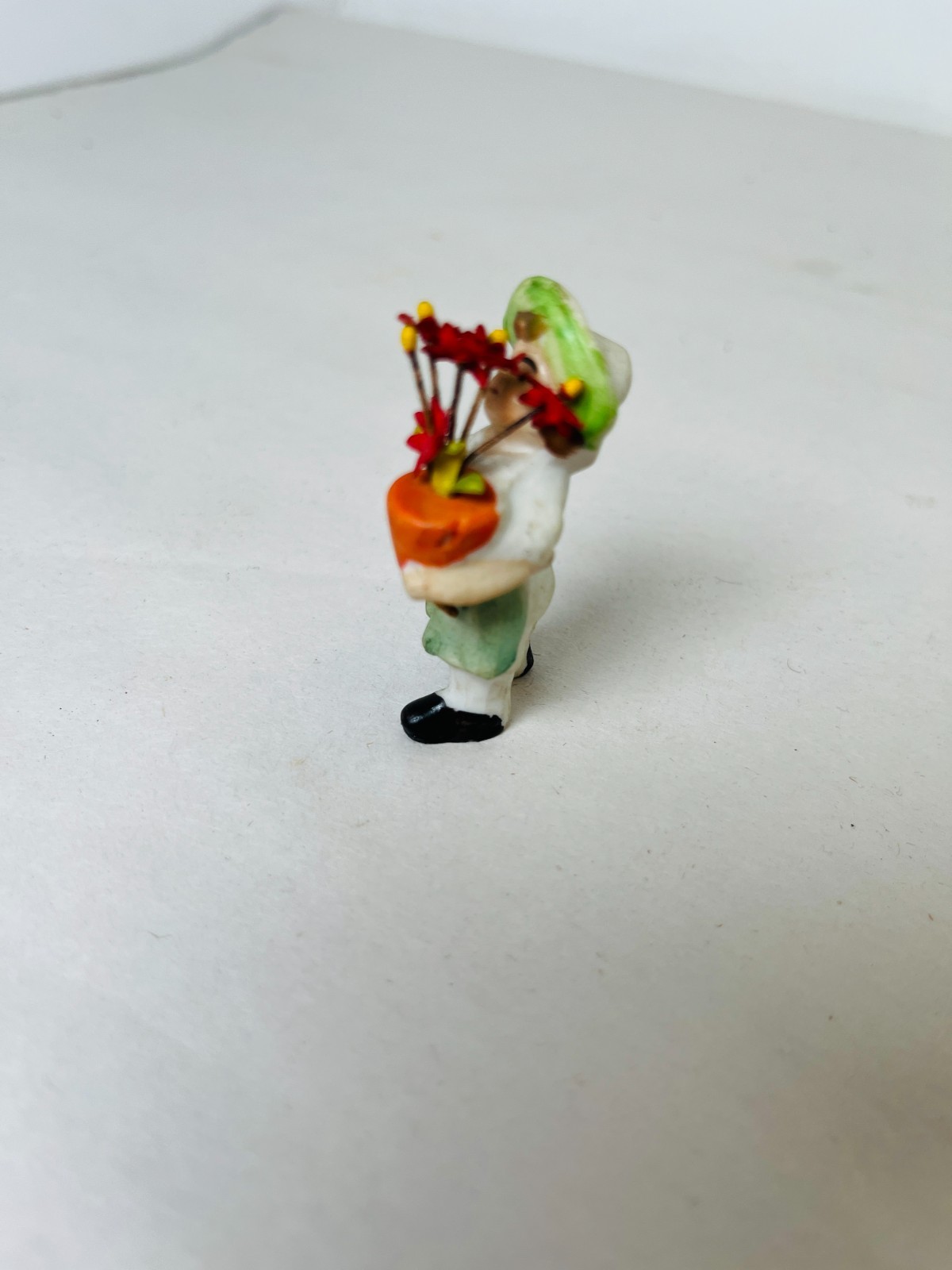 Antique Small porcelain Figure Holding A Pot Of Flowers 2″ Tall