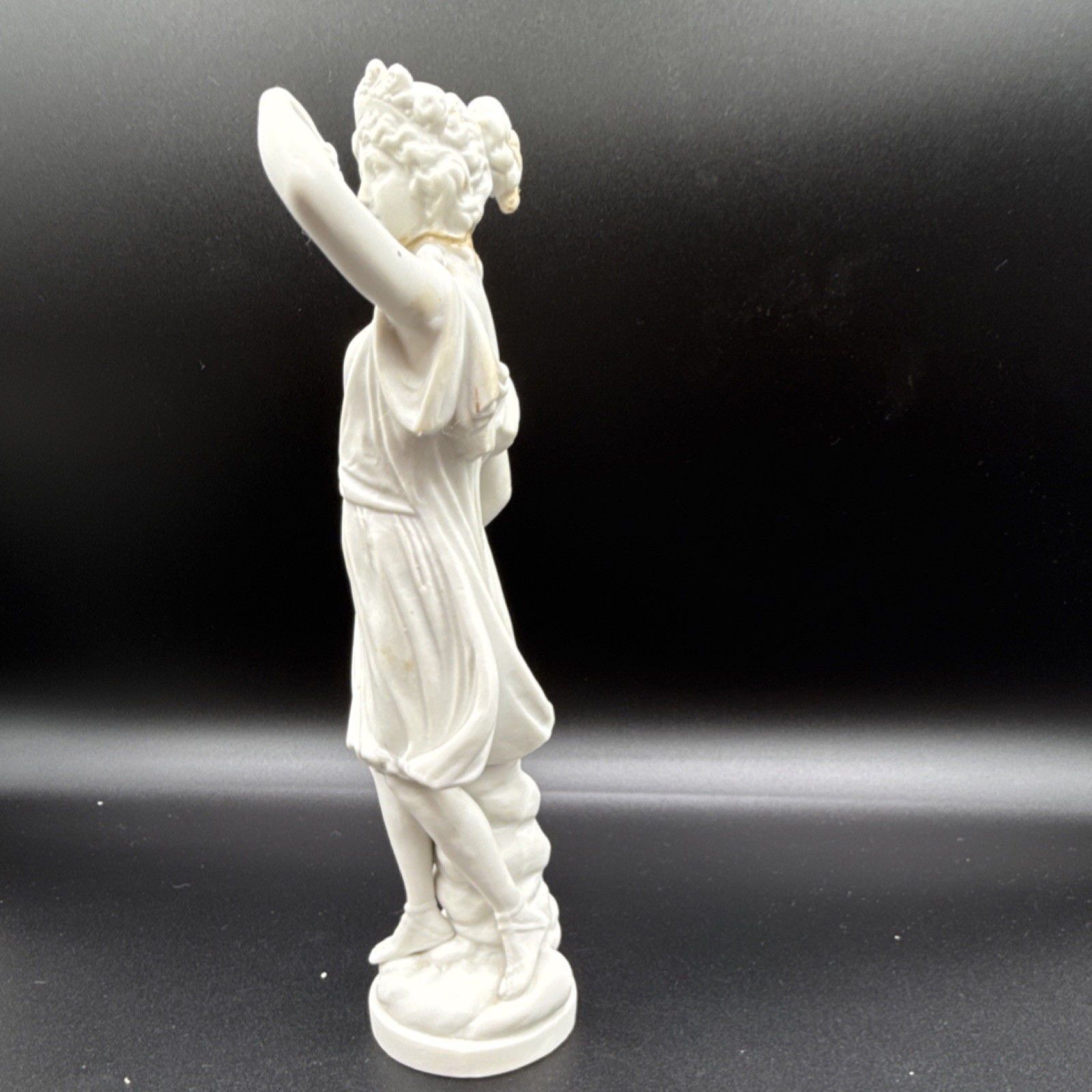 White porcelain figurine of a woman with cornucopia and carved details