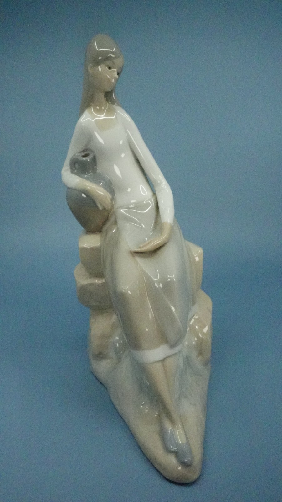 NAO Lladro porcelain figurine, “Girl Sitting on Rocks With Jug”, 9.75″ T, 4.5″ W