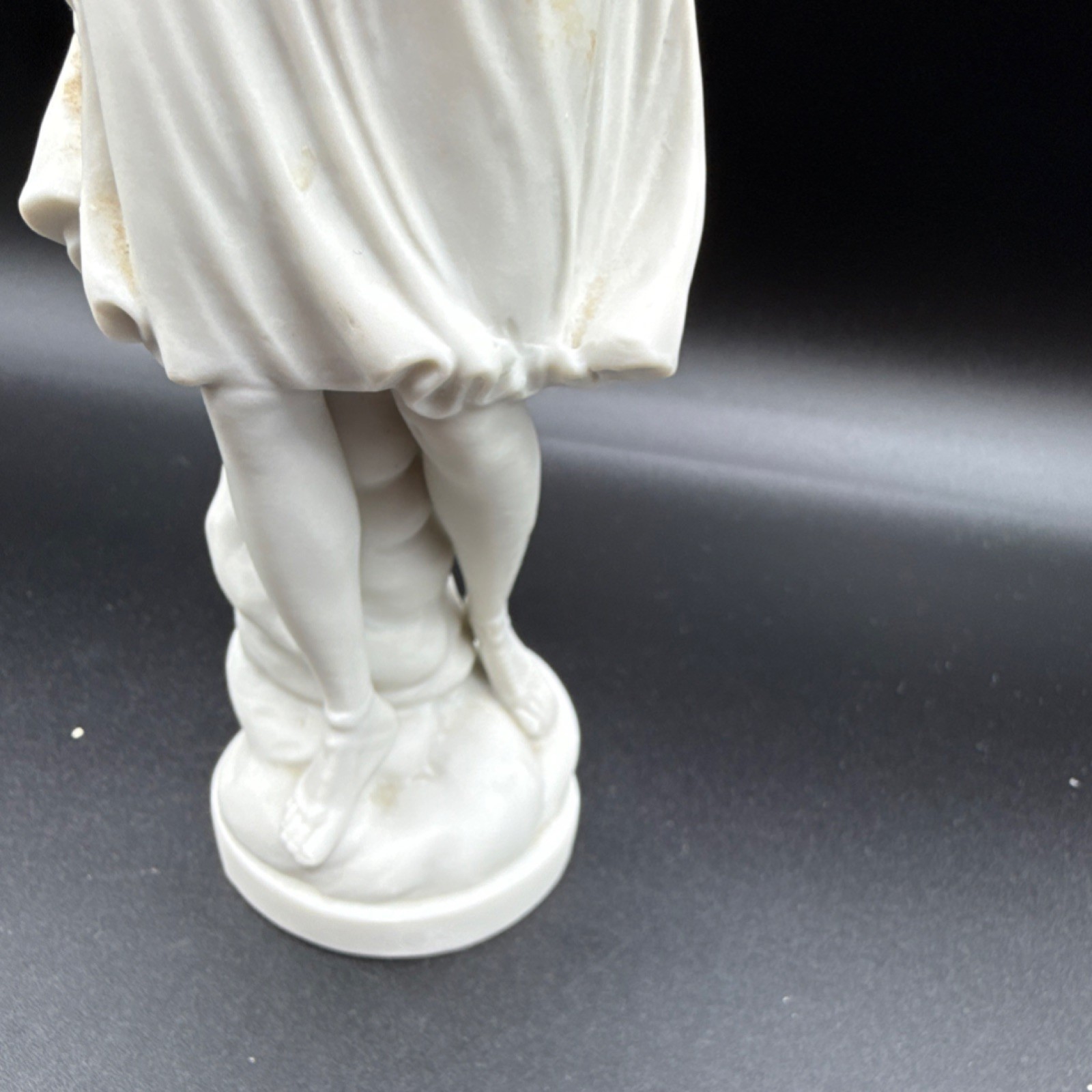 White porcelain figurine of a woman with cornucopia and carved details